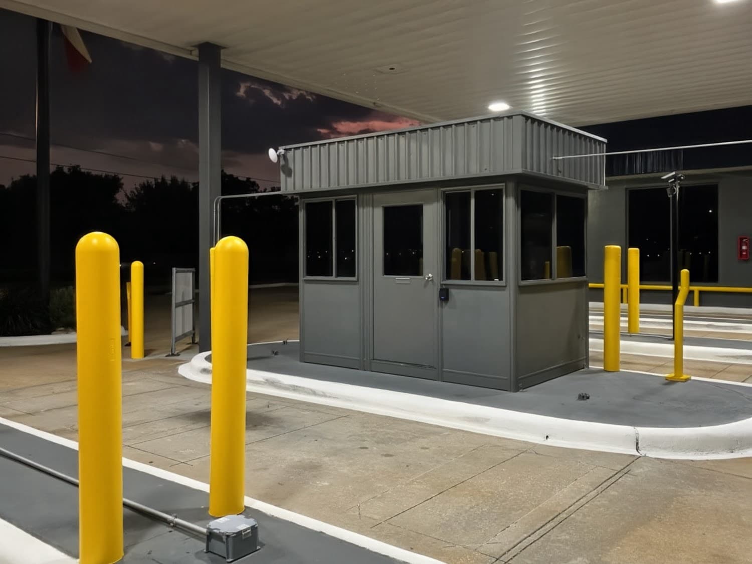 Lit, staffed entry booth under the canopy at Hobby Airport Parking at dusk