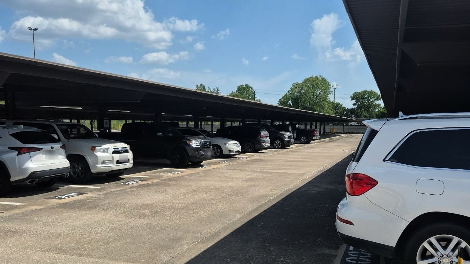 A full row of cars parked under the steel canopies in the covered section at Hobby Airport Parking