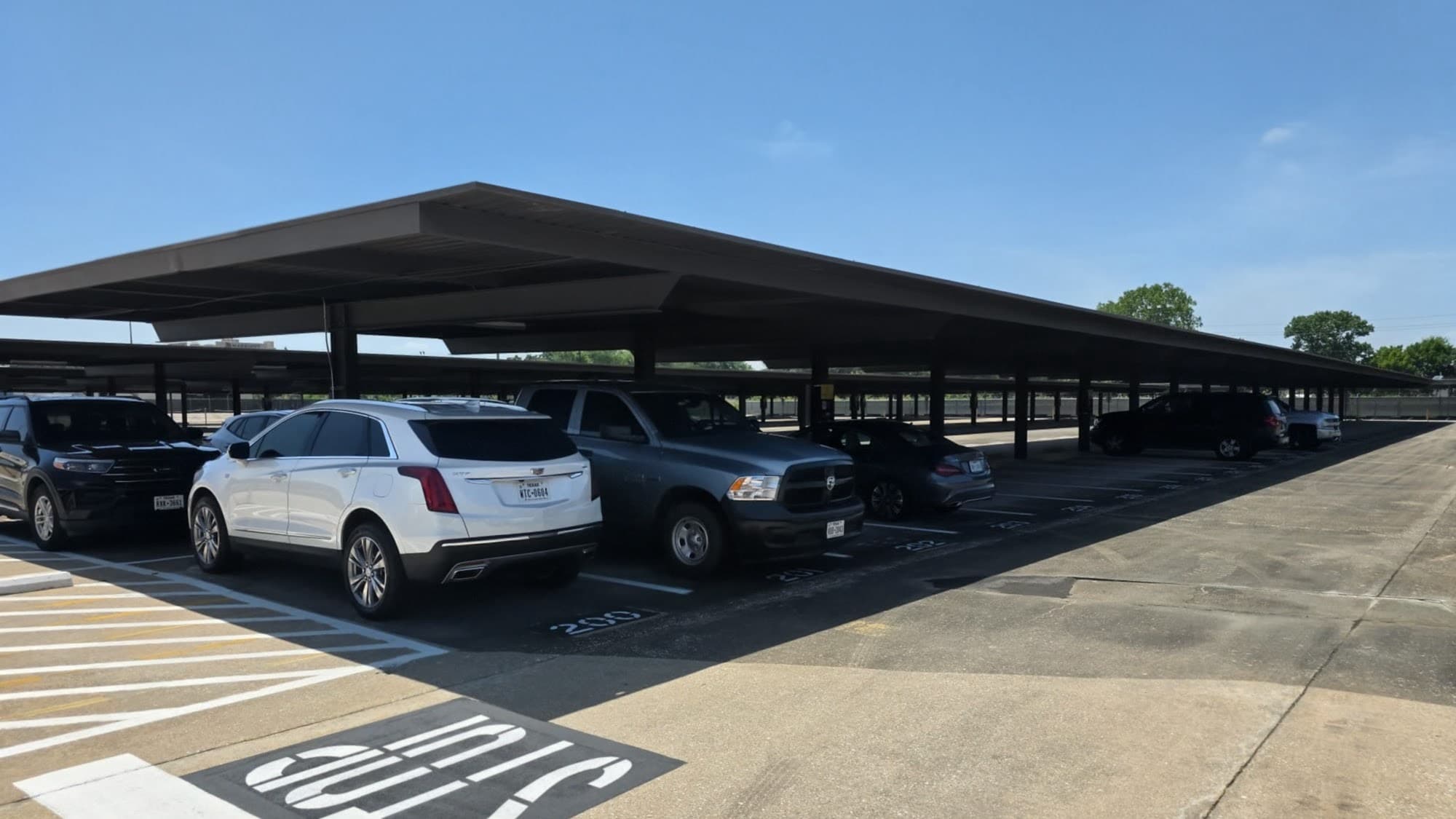 Cars parked under lit steel canopies in the covered section at Hobby Airport Parking