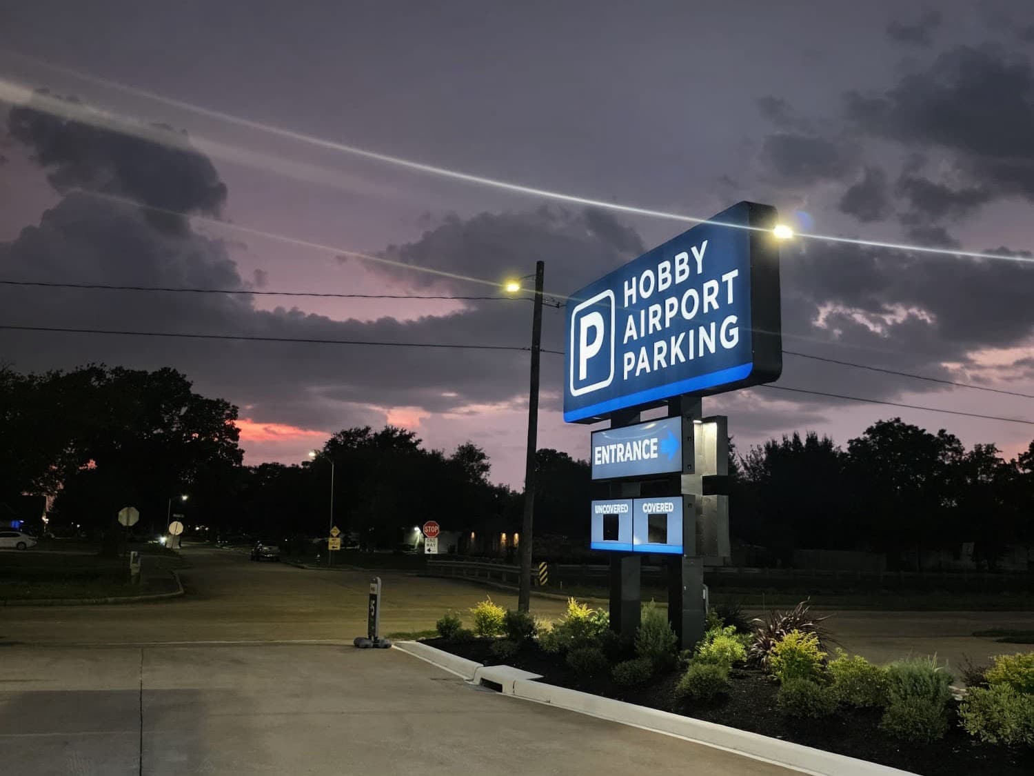 Illuminated Hobby Airport Parking monument sign at dusk showing the entrance and covered/uncovered options