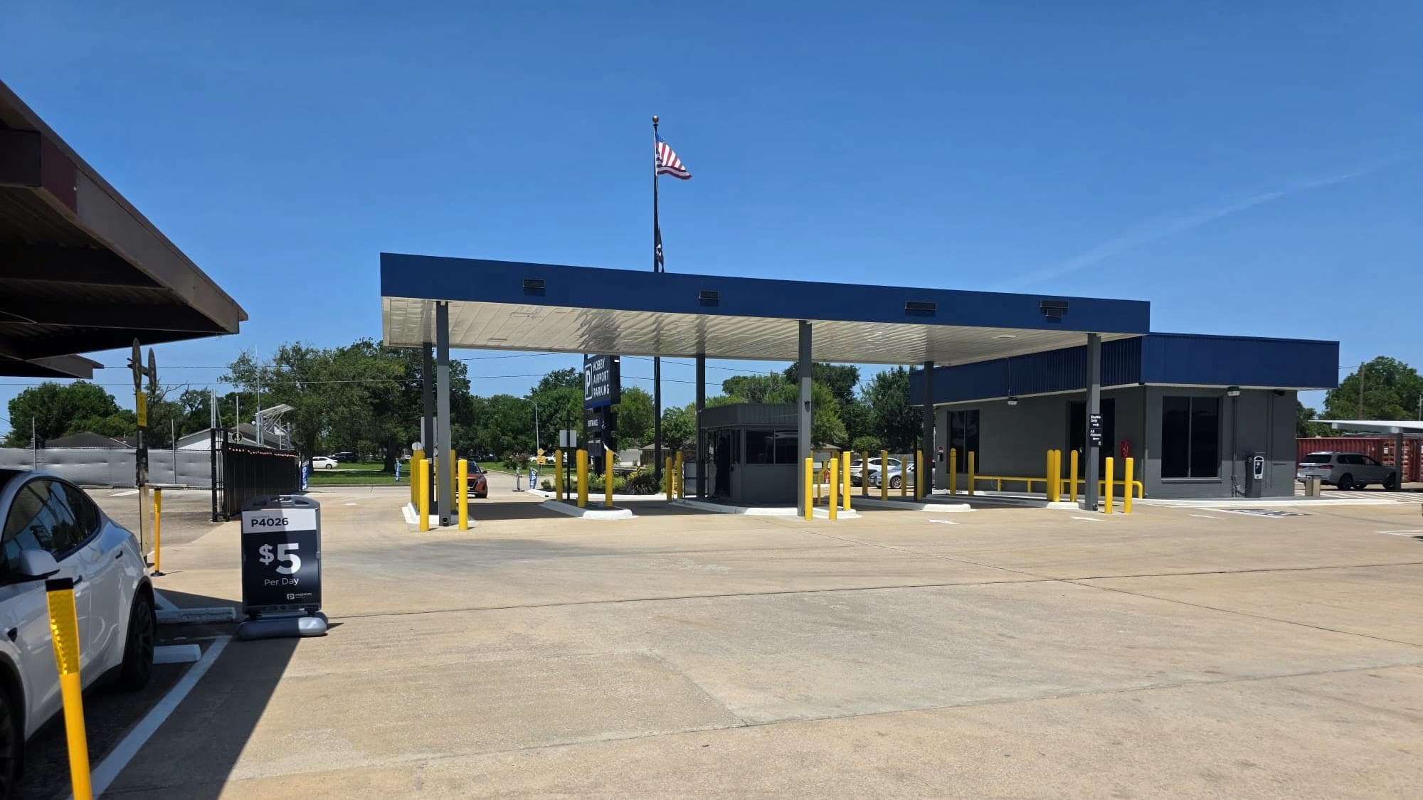 Wide daytime view of the Hobby Airport Parking entrance, covered canopies, and US flag near Houston Hobby Airport