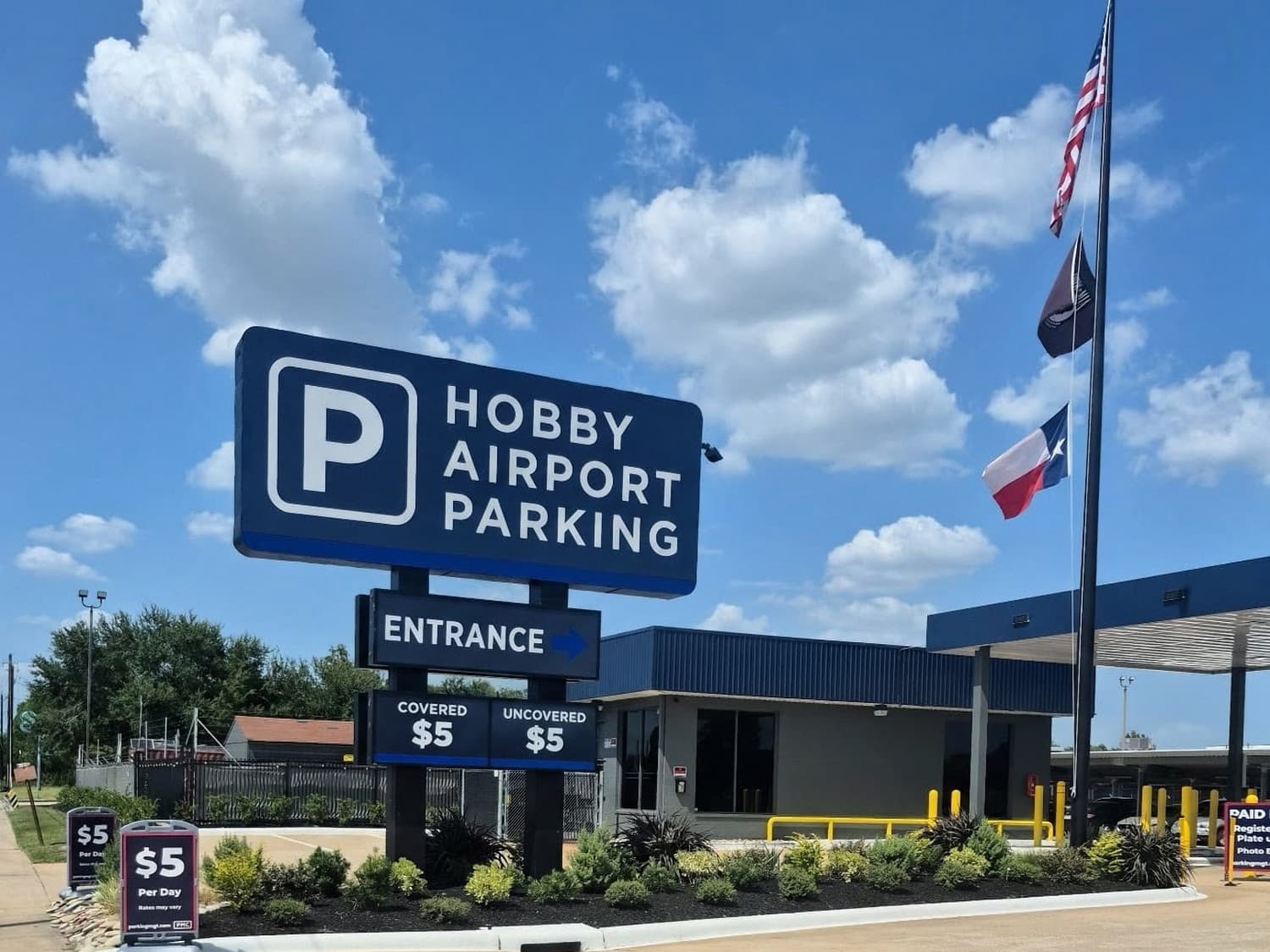 The Hobby Airport Parking monument sign in daylight, showing the P logo, an entrance arrow, and the posted covered and uncovered daily rates